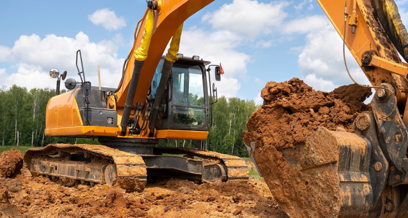 Excavator bucket full of soil on a dig site