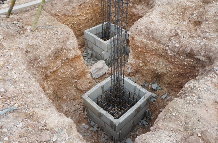 Rebar-reinforced concrete block footings in excavated pits