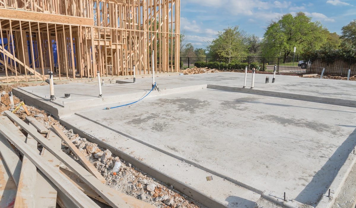 Concrete slab-on-grade foundation beside a framed house