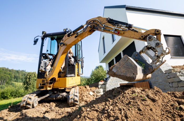 Mini excavator digging beside a house foundation