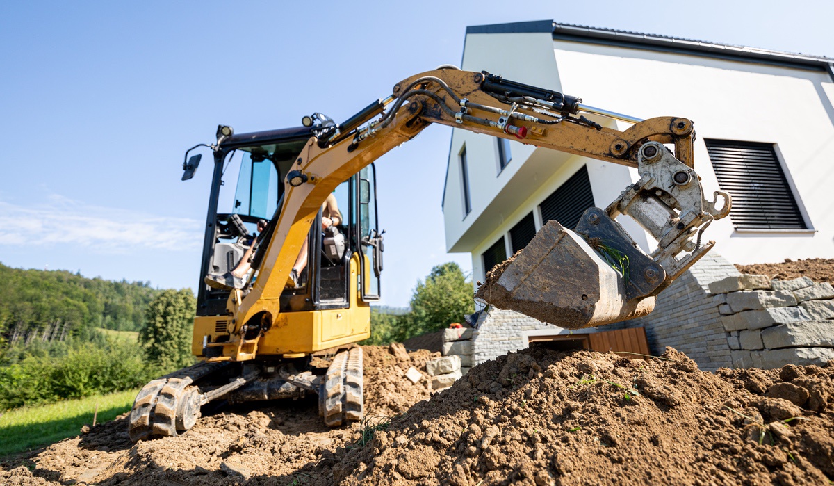 Mini excavator digging beside a house foundation