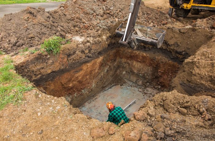 Worker in a deep excavation for a septic tank