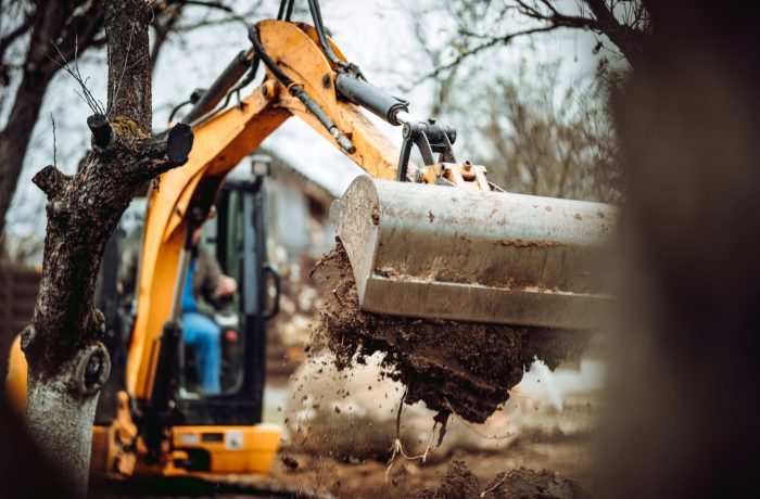Mini excavator lifting soil while clearing a yard
